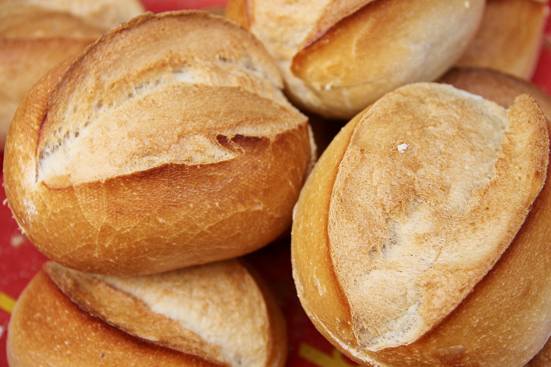 Picture of fresh-baked bread. Several loaves piled on each other on a red background. Food in fiction is important