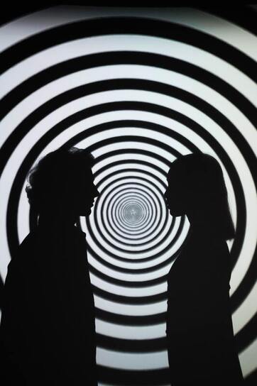 Silhouettes of man and woman against black and white spiral background. An image from the published poetry of Cortni Merritt.