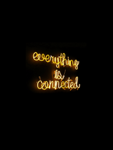 Black background yellow neon sign "everything is connected"