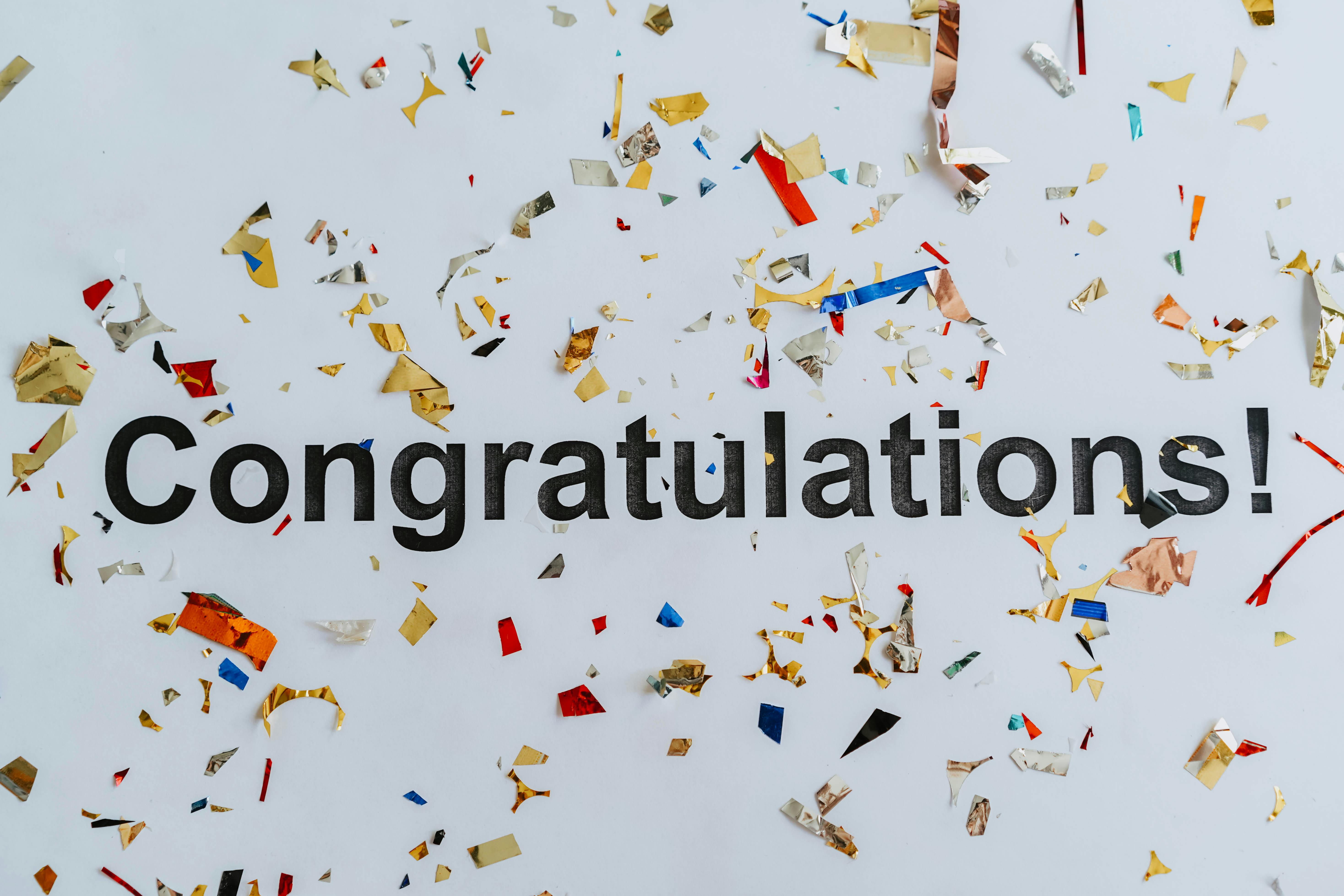 Black letters spell out "Congratulations" against a white background with colored confetti surrounding.